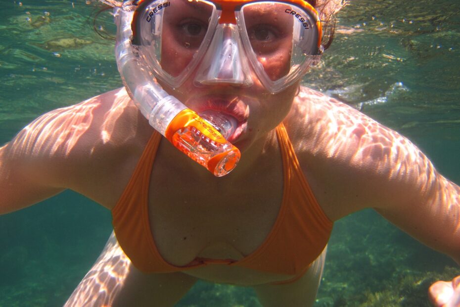 Pige med svømmebriller dykker