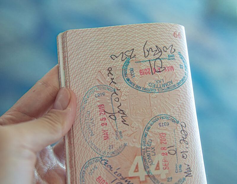 A close-up view of a hand holding an open passport with various stamps, highlighting travel experiences.
